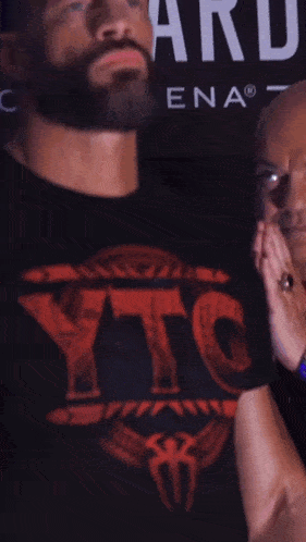 a man in a ytc shirt stands in front of a sign