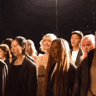 a group of people are standing in a line and one has pink hair