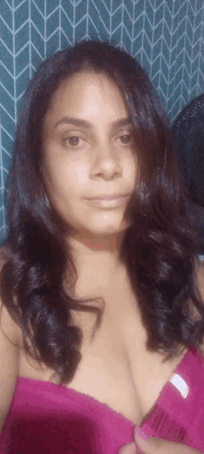 a woman wearing a pink bra is taking a picture of herself
