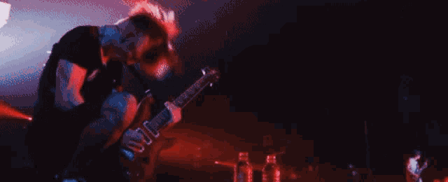 a man in a black shirt is playing a guitar on a stage