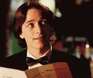 a man in a tuxedo and bow tie is reading a menu for a restaurant called the mediterranean