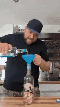 a man is pouring liquid into a bottle with a funnel