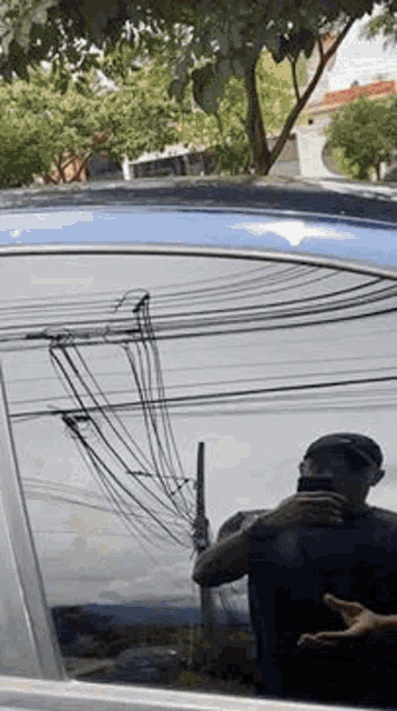a man is taking a picture of himself in a car window with a cell phone .