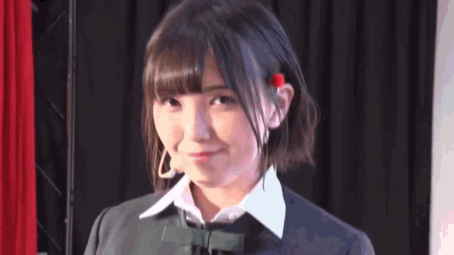 a young girl with a red flower in her hair is smiling