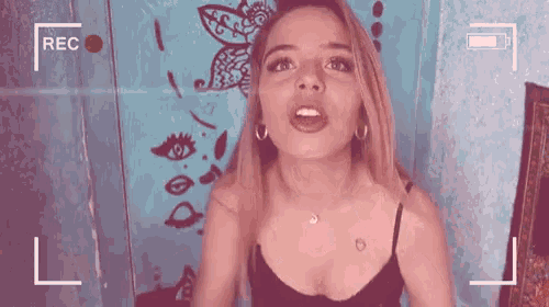 a woman in a black tank top is being recorded with a rec button in the corner