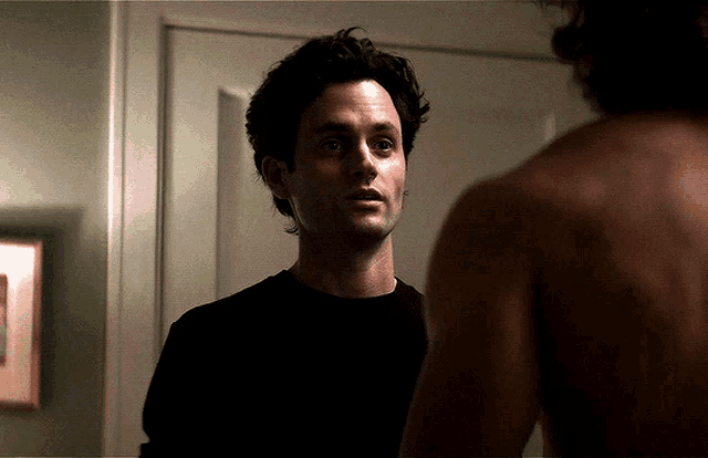 a man in a black shirt stands in front of a mirror