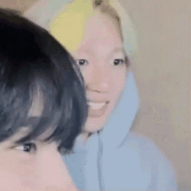 a close up of two people 's faces with one wearing a hoodie .