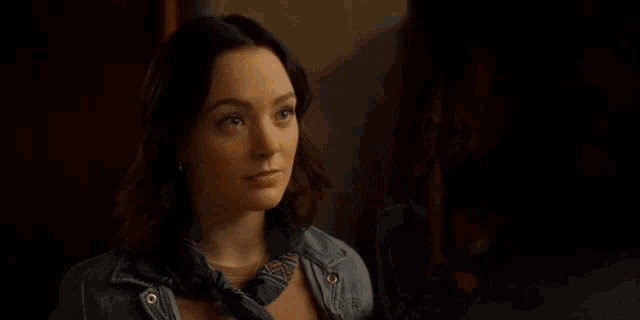 a woman is standing next to another woman in a room and looking at herself in the mirror .