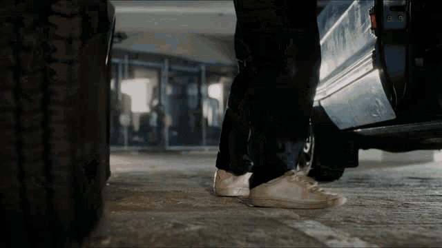a person standing in front of a car with a tire on the ground