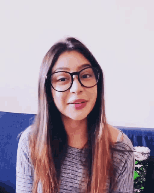 a woman wearing glasses and a striped shirt is making a funny face