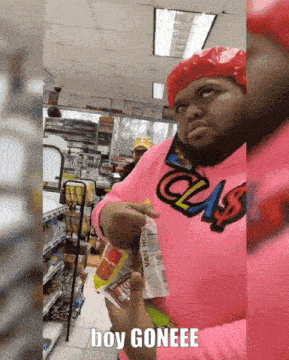 a man wearing a pink shirt that says class is holding a bag of chips