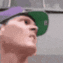 a close up of a person wearing a purple hat and a green hat .