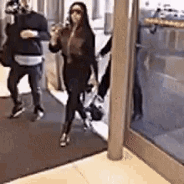 a group of people are walking through a doorway and a woman is standing in the doorway .