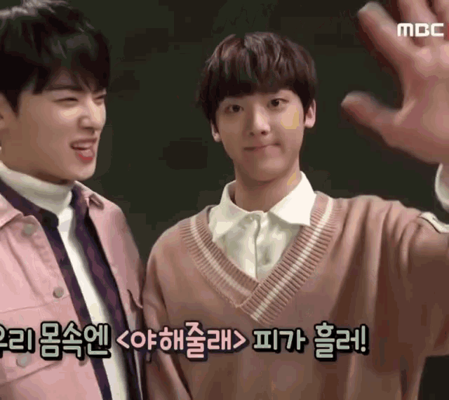 two young men are standing next to each other and one of them is wearing a pink jacket and a sweater .