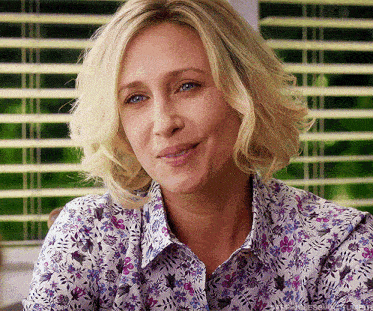 a woman wearing a floral shirt is smiling and looking at the camera
