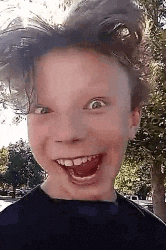 a young boy with long hair is making a funny face .