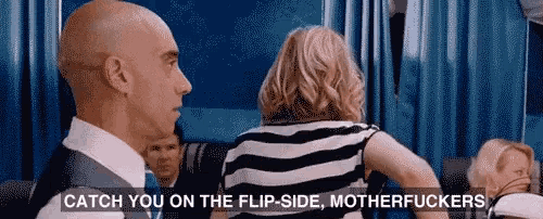 a man in a suit and tie is talking to a woman in a striped dress on an airplane .