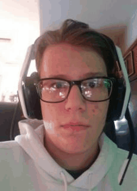 a man wearing glasses and headphones is taking a selfie .