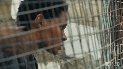 a close up of a woman behind a fence with netflix written on the bottom
