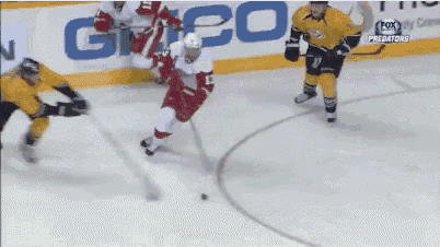 a hockey game is being played in front of a sign that says geico