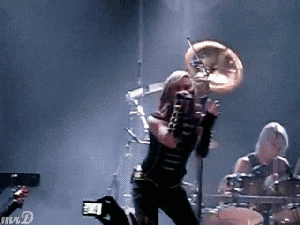 a woman singing into a microphone while playing a drum