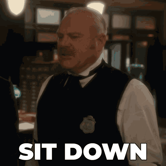 a man in a vest with a badge that says sit down on it