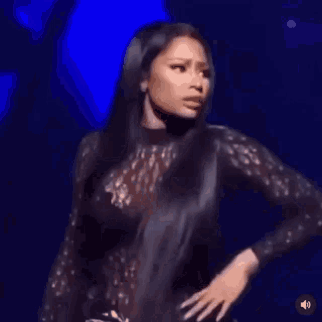 a woman with long black hair is standing on a stage with her hand on her hips .