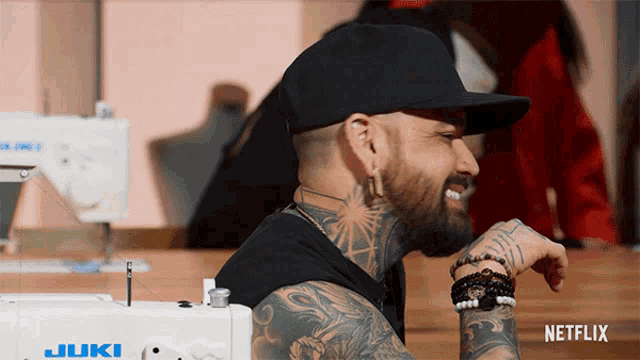 a man sitting in front of a sewing machine that says juki on it