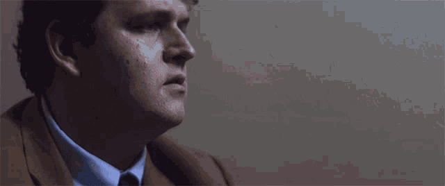 a man in a suit and tie sits in a dark room