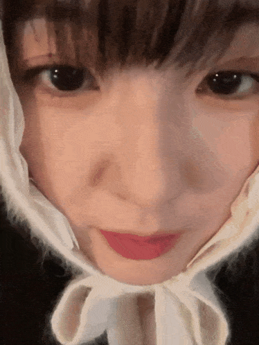 a close up of a woman 's face wearing a white scarf around her head .
