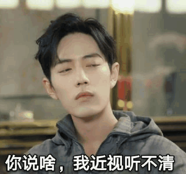 a young man is making a funny face with his eyes closed while wearing a hoodie .