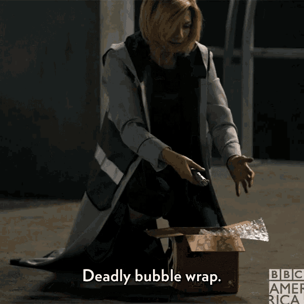 a woman is kneeling down next to a cardboard box that says deadly bubble wrap