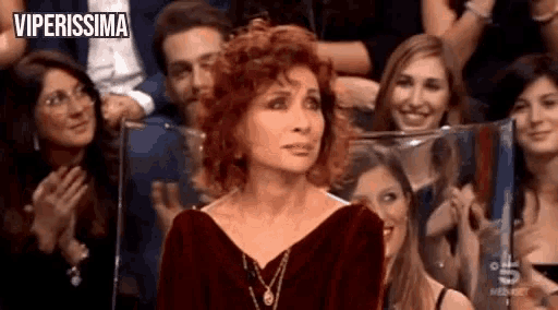 a woman with red hair is sitting in front of a crowd of people with the words viperissima above her