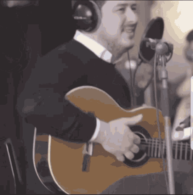 a man wearing headphones playing an acoustic guitar
