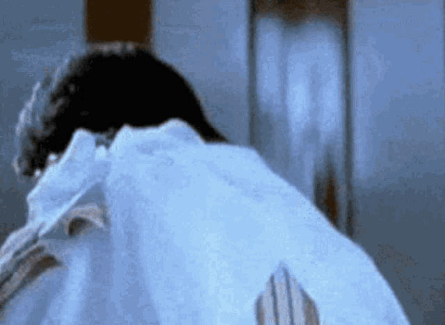 a man in a white shirt is standing in front of a mirror in a room .