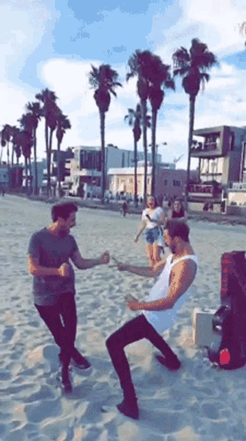 a group of men are dancing on a sandy beach .