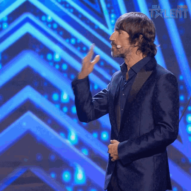 a man in a suit stands on a stage in front of a sign that says ' star talent ' on it