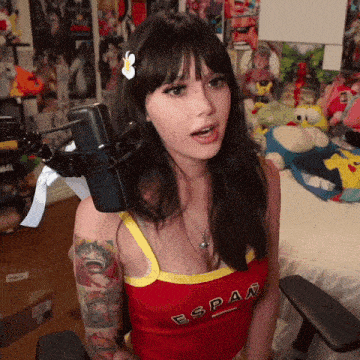 a woman with a flower in her hair is wearing a red tank top that says espan