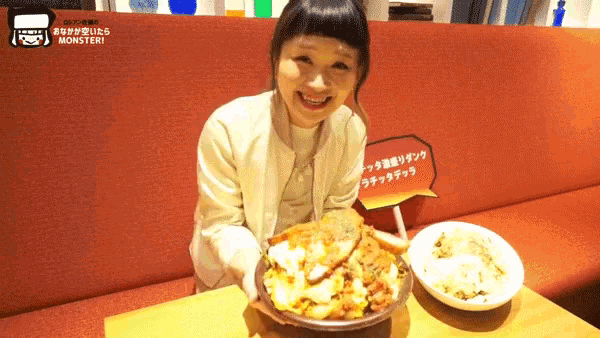 a woman sitting at a table with a plate of food and a sign that says monster