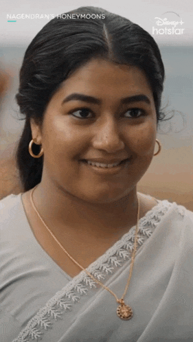 a close up of a woman wearing a necklace and hoop earrings