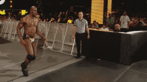 a referee stands behind a man in a wrestling trunks