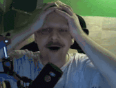 a man with a mustache is holding his head with his hands