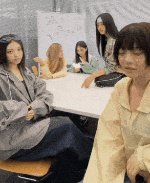 a group of girls are sitting around a table with a white board that says dior on it