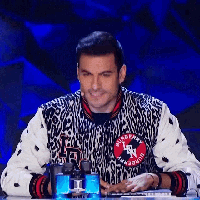 a man wearing a burberry jacket is sitting at a desk