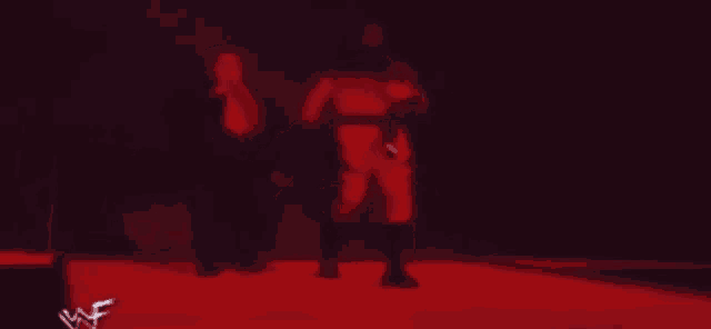 a man in a red suit is walking in a dark room with a w logo on the bottom