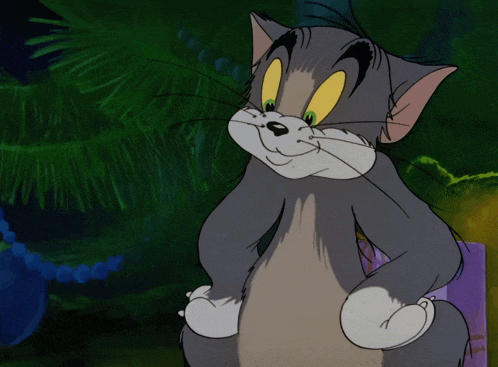 a cartoon cat named tom is smiling with his hands on his hips in front of a christmas tree