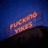 a neon sign that says `` fucking yikes '' is lit up at night on top of a building .