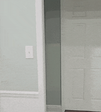 a man in a white shirt is peeking out of a doorway