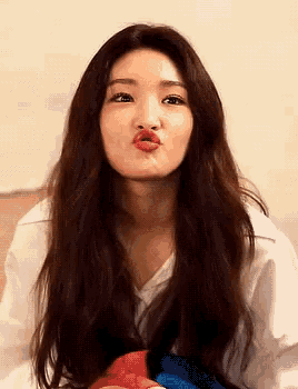 a woman with long brown hair is making a funny face with her lips .