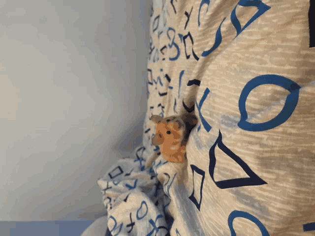 a stuffed animal is peeking out from under a blanket with letters and numbers on it